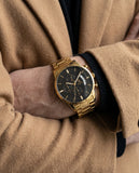Laguna Drip gold watch with black dial worn with a camel coat.